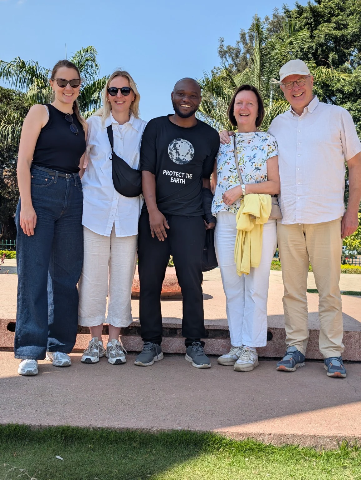 Frazier Msuya in a black Protect the Earth T-shirt, standing with four guests