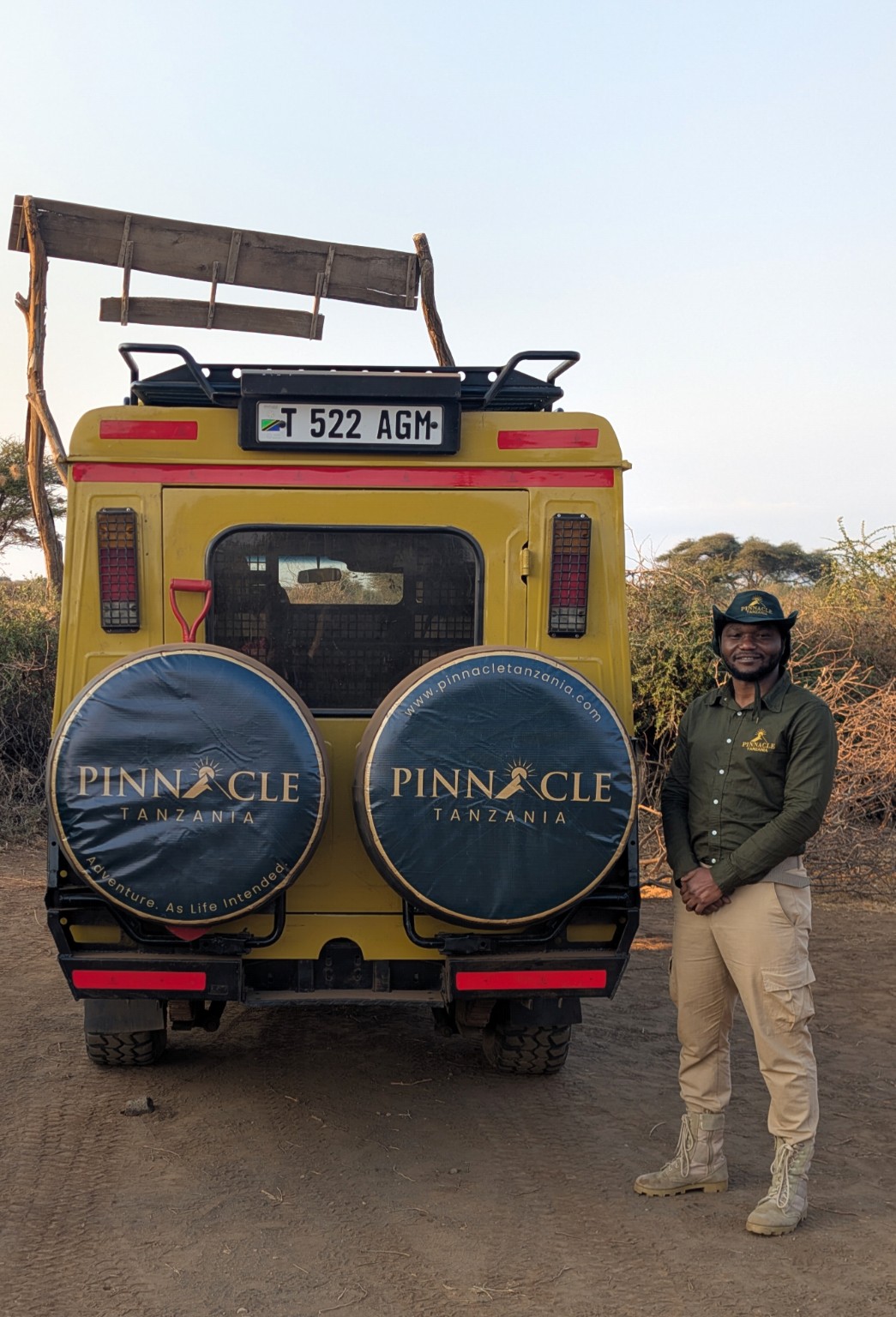 Frazier Msuya beside a branded Pinnacle Tanzania safari vehicle